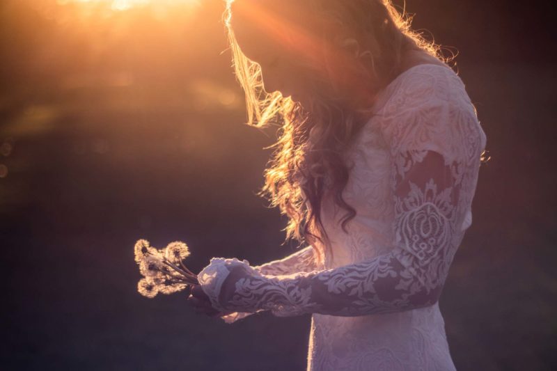 Bride in a wedding dress holding dandelions